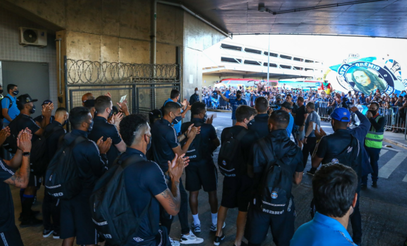Jogadores do Grêmio descem do ônibus e agradecem apoio antes da viagem; dirigente abraça torcedores Grêmio