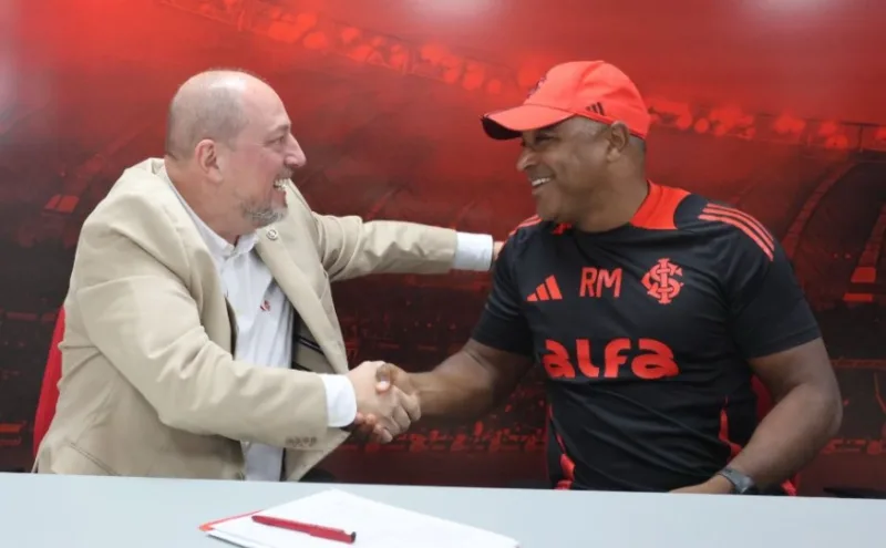 Dirigente do Inter explica renovação "antecipada" com Roger Machado Roger Machado renova contrato até 2026 com o Inter. Na foto, aparecem Alessandro Barcellos e Roger Machado apertando as mãos sentado lado a lado em uma mesa, após a nova assinatura de contrato.