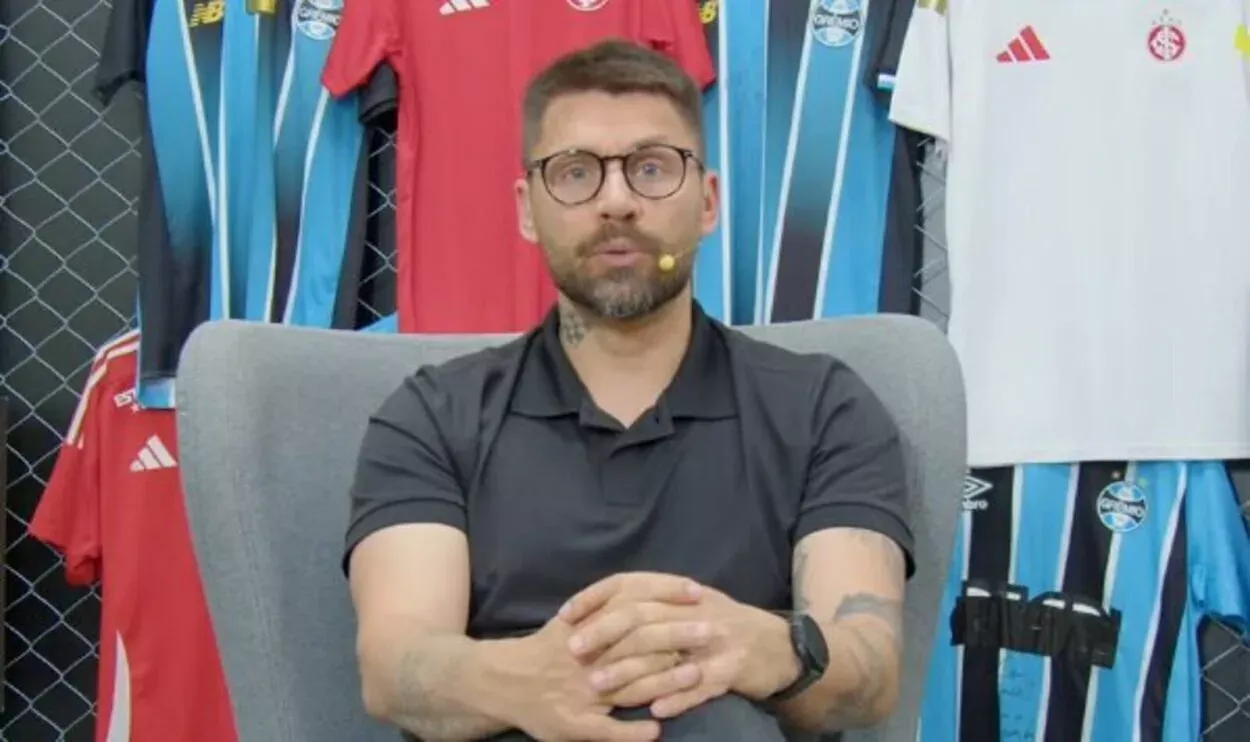 Rafael Sobis, ex-jogador do inter — Rafael Sobis, ex-jogador do Inter sentado olhando para câmera de TV, com camisetas do Grêmio ao seu redor